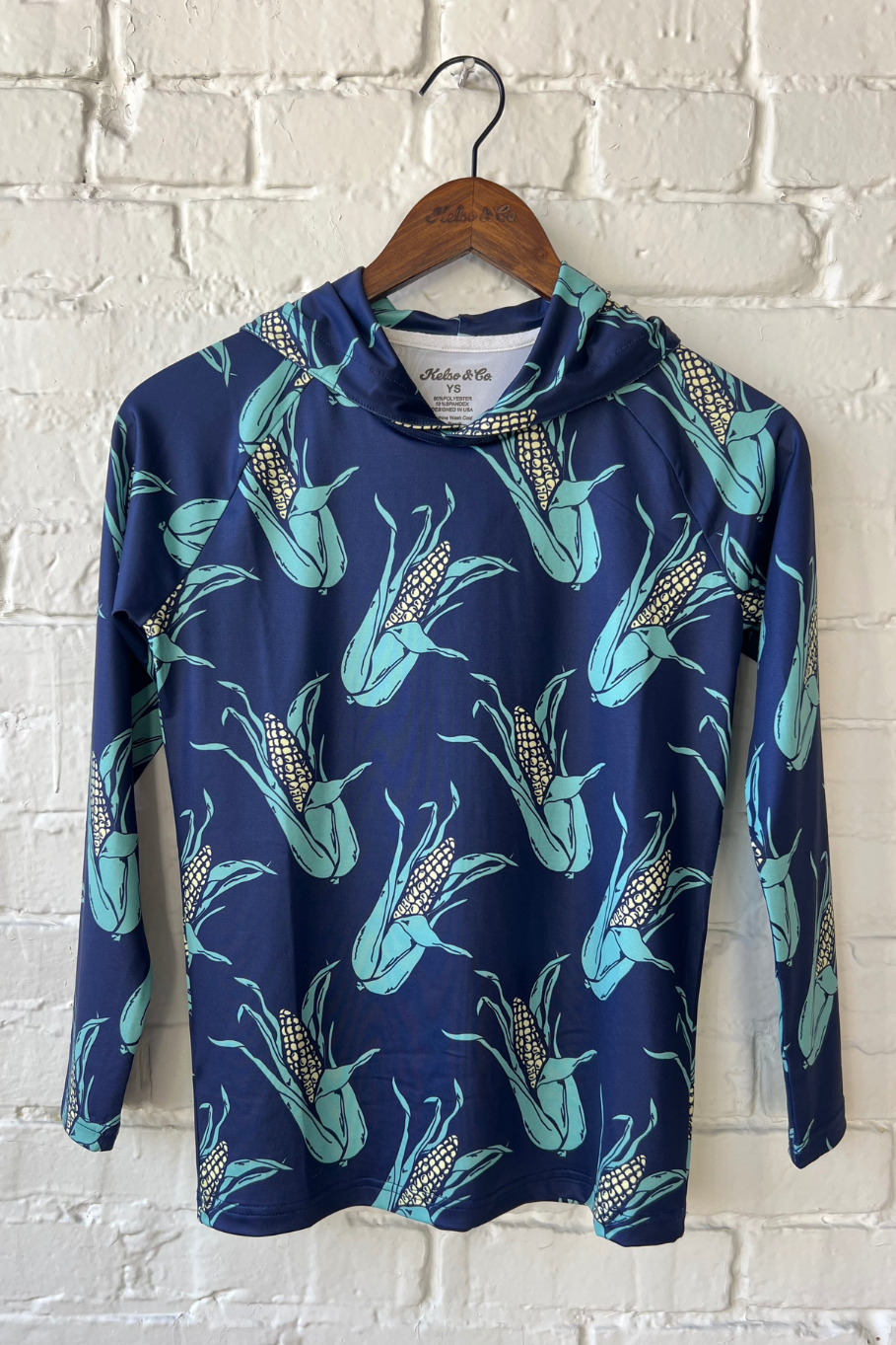 Youth performance hoodie with navy blue background and an all over ears of corn pattern.