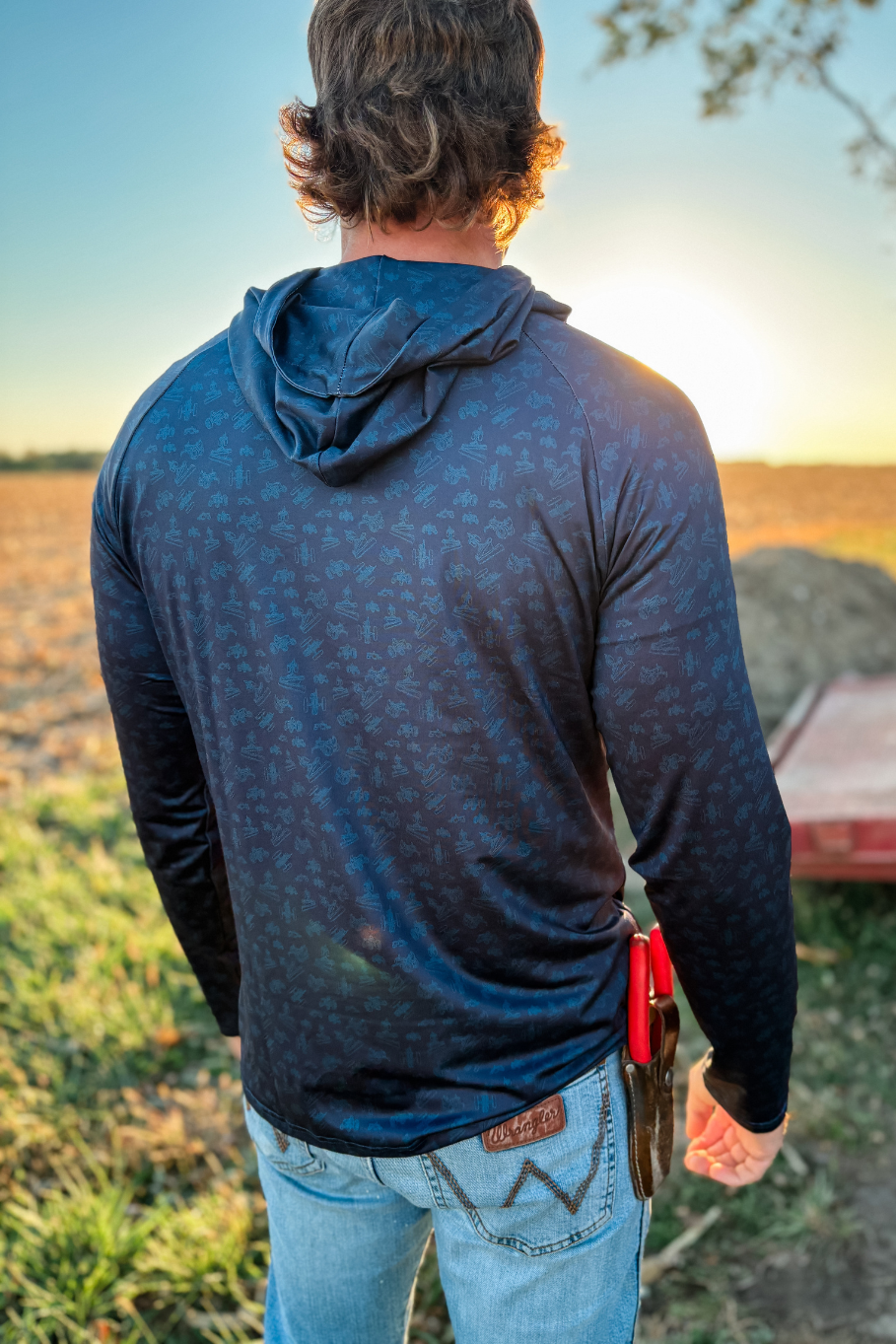 man in blue performance hoodie facing the sunset wearing antique tractor print