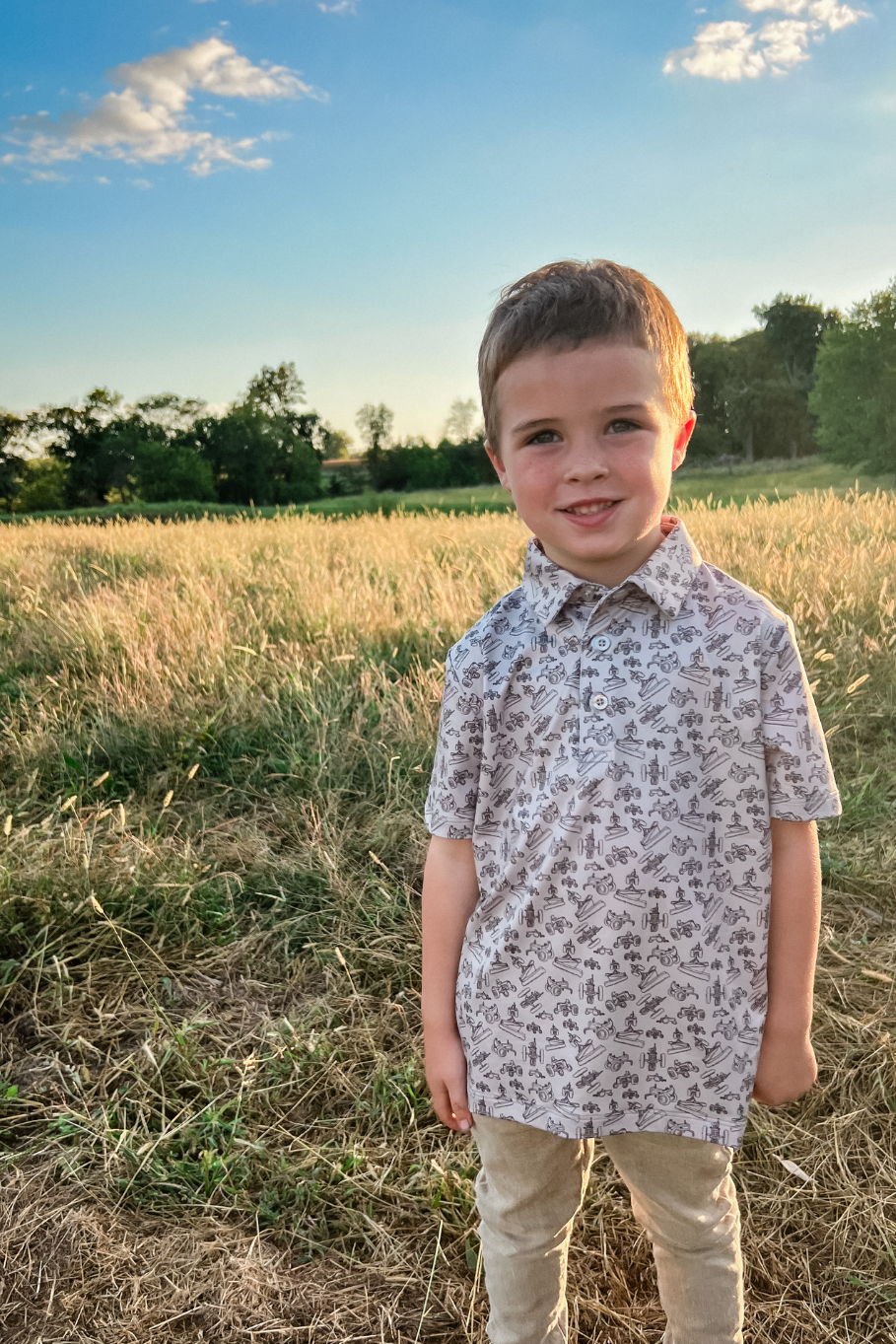 boy standing in a grass field at sunset