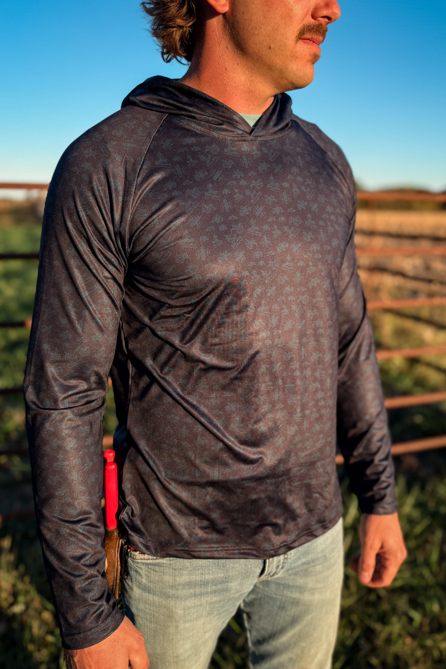 man wearing performance hoodie with antique tractor print in blue