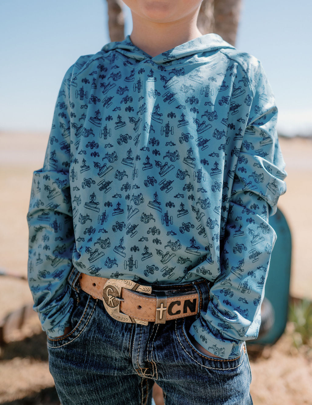 boy wearing a blue performance hoodie with dark blue tractors all over it