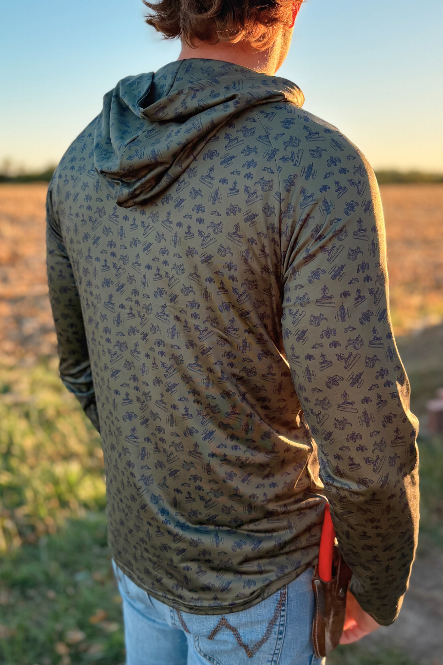 man facing the sunset wearing a performance hoodie with antique tractor print