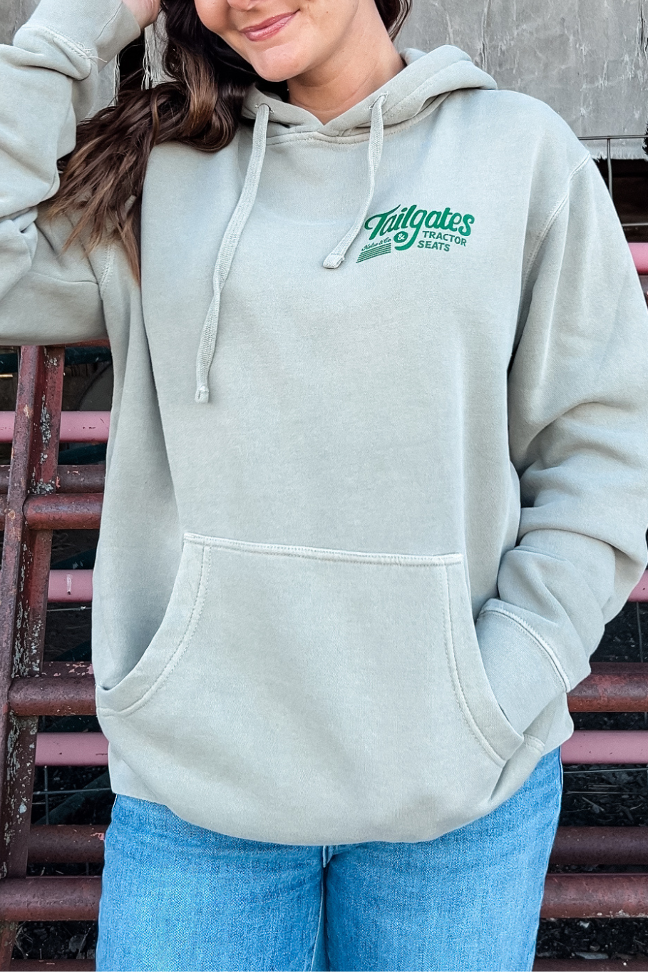 women standing in front of cattle panels with a hoodie on that says tailgates and tractor seats