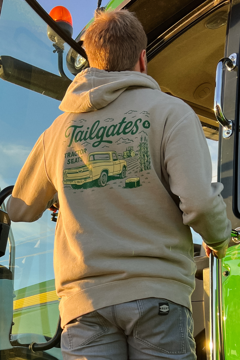 guy climbing into a tractor with cement hoodie on that says "tailgates and tractor seats"