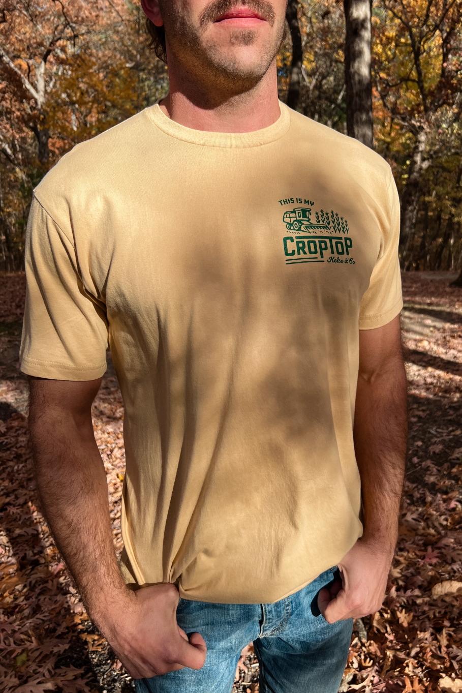 front of guy wearing light camel graphic tshirt with graphic of combine harvesting corn that says this is my crop top