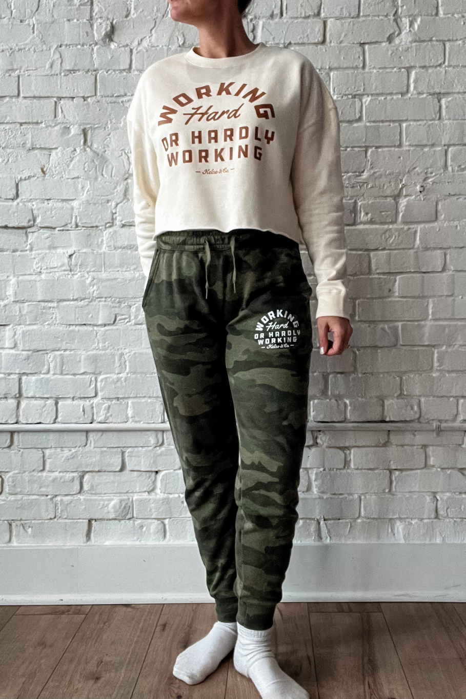 womens camo joggers that say working hard or hardly working on left thigh near pocket in white