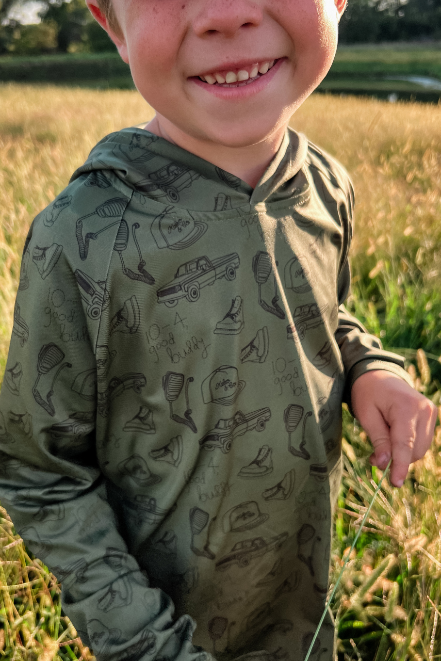 boy wearing olive green performance hoodie in hay field