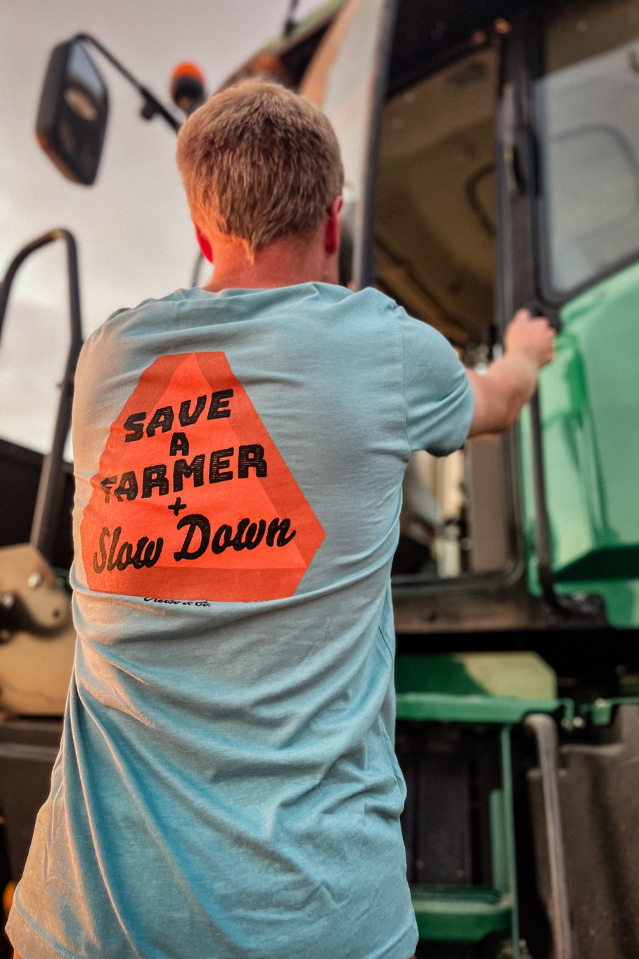 unisex farm graphic tshirt with &quot;Save a Farmer and Slow Down&quot; slow moving vehicle sign on the back