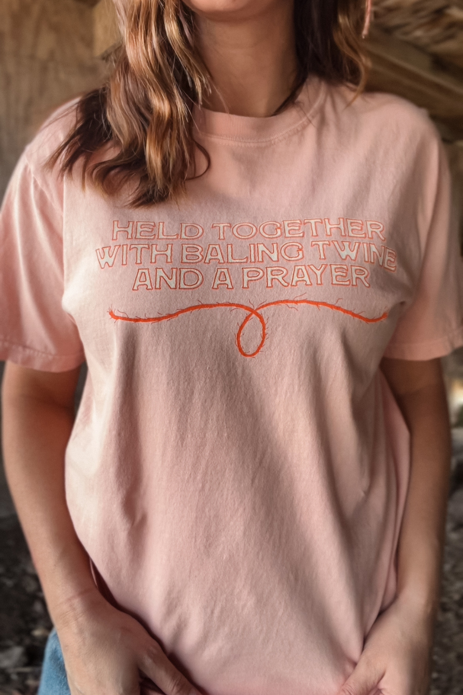 Held together with baling twine and a prayer western graphic tee in peach