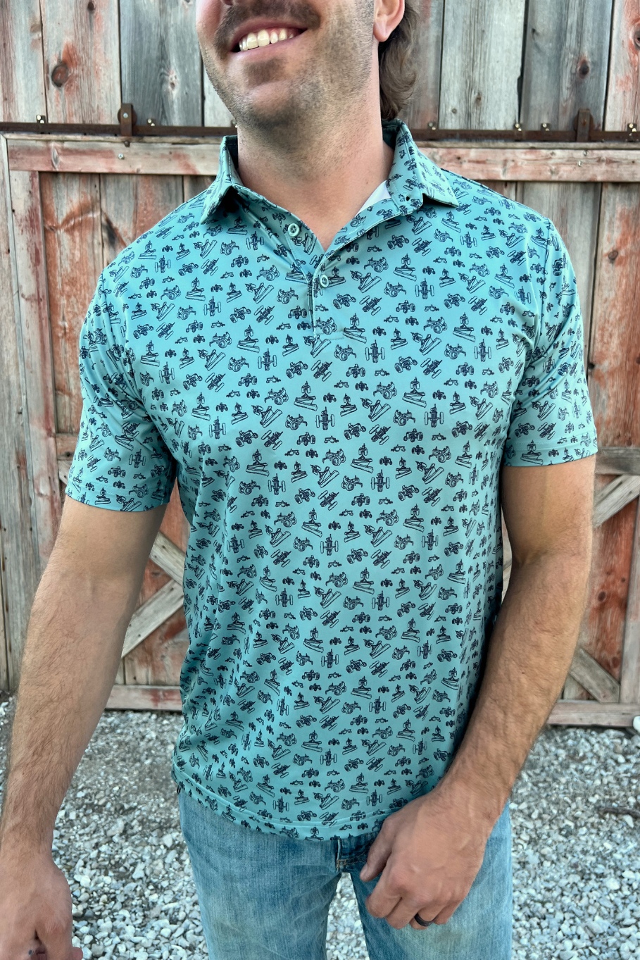 Man smiling wearing a green polo with a vintage tractor pattern. 