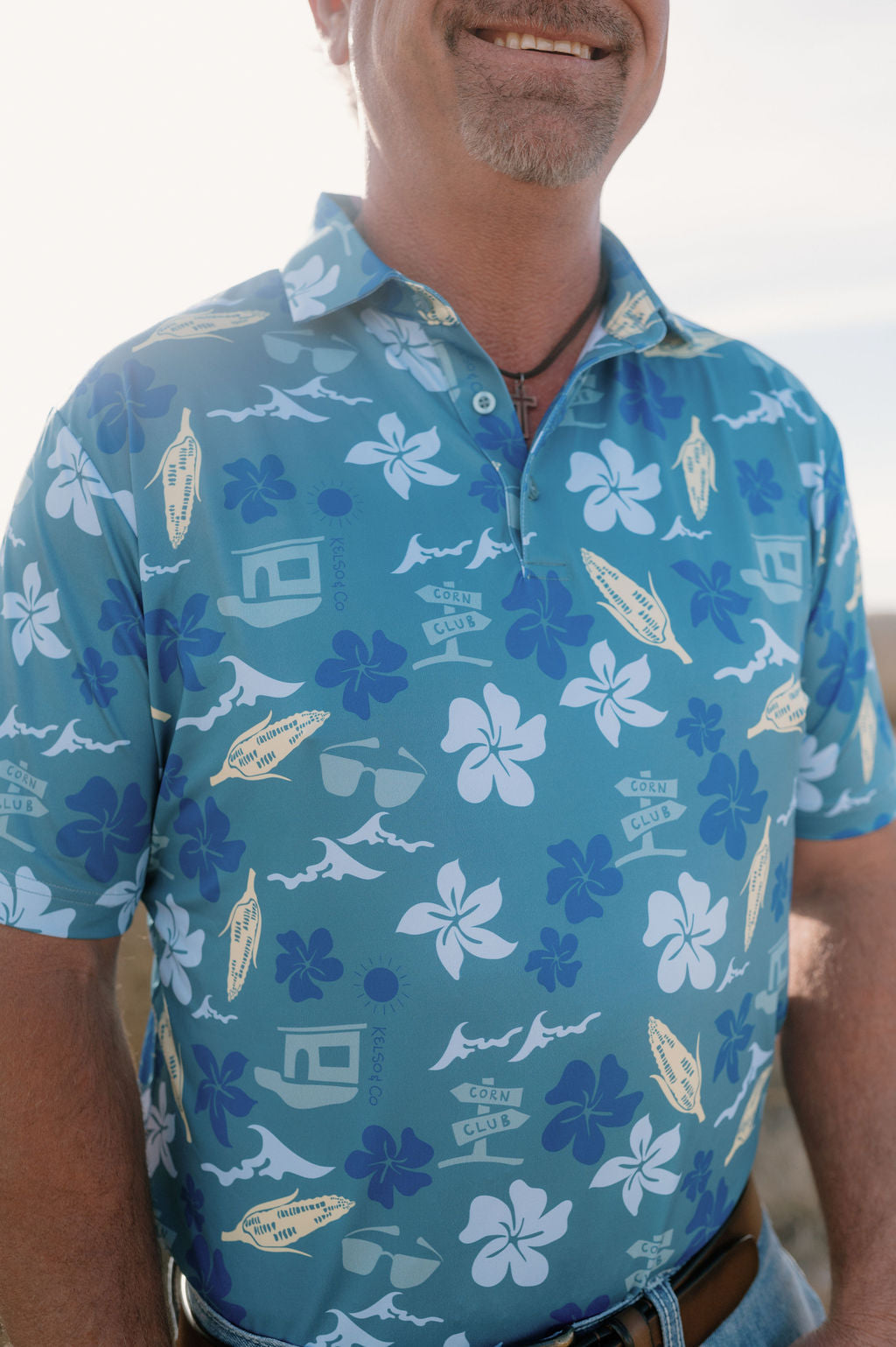 Picture of man wearing blue Hawaiian inspired polo. 