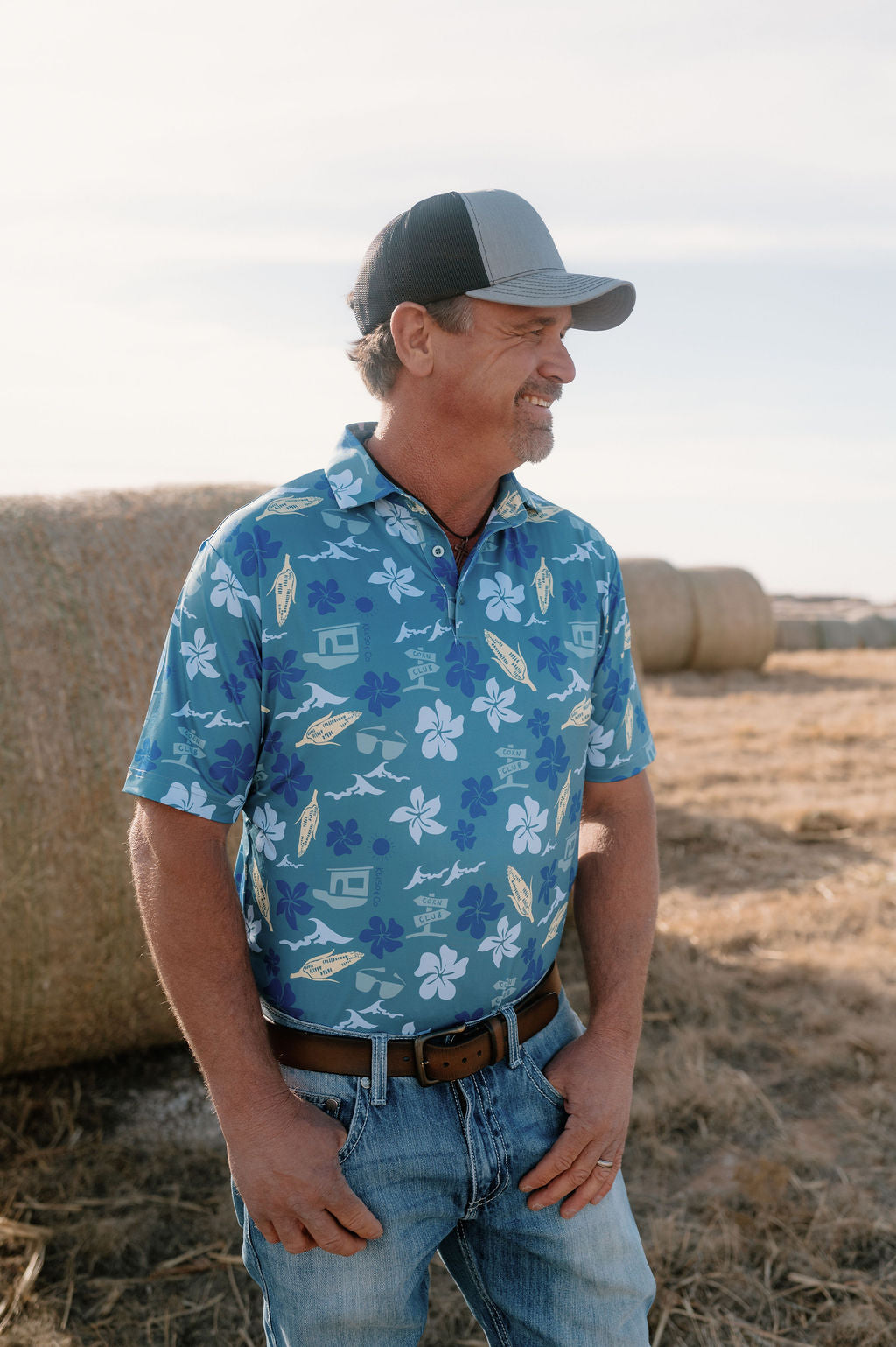 Picture of man looking to the side wearing a blue Hawaiian inspired polo. 