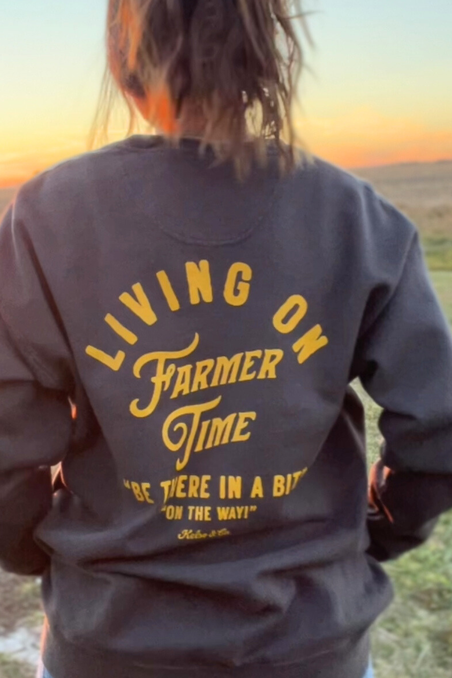girl on a farm in gray sweatshirt that says living on farmer time on the back