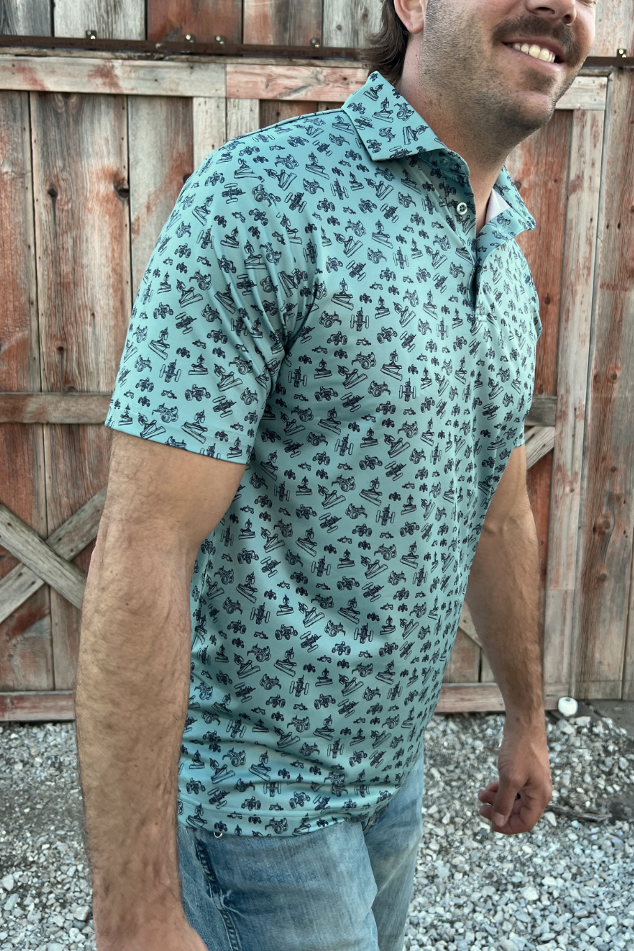 Picture of a man turning to the side wearing a green polo with a vintage tractor design. 