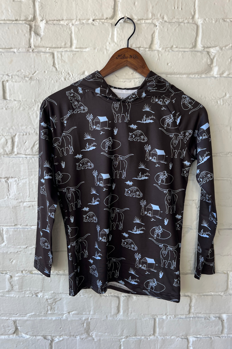 Youth performance hoodie in dark brown with western icons including longhorns, cowboys, armadillos, and a western scene. 