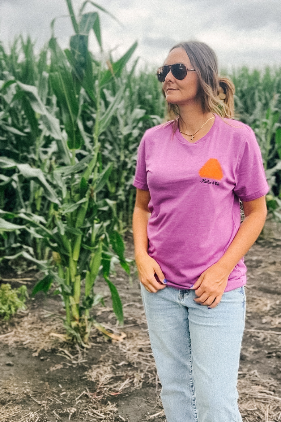 Front of the shirt save a farmer and slow down in magenta with slow moving vehicle sign in a cornfield