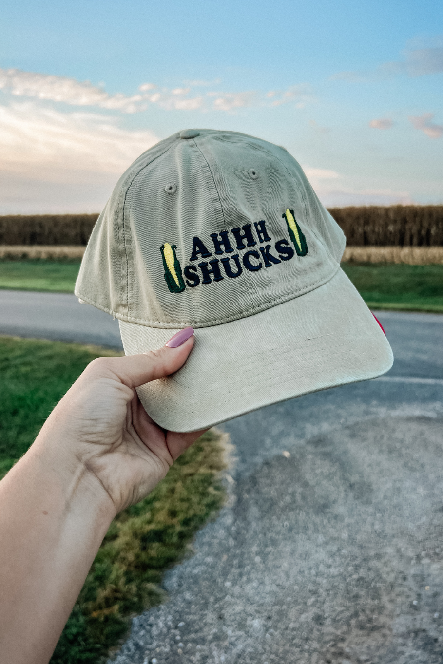 Khaki dad hat in front of a partially harvested corn field