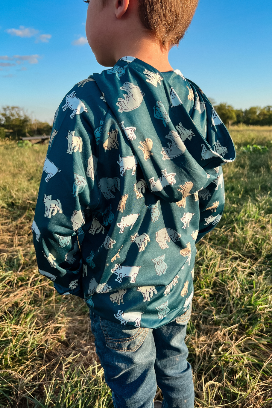 back of hog wild performance hoodie boy standing in hayfield