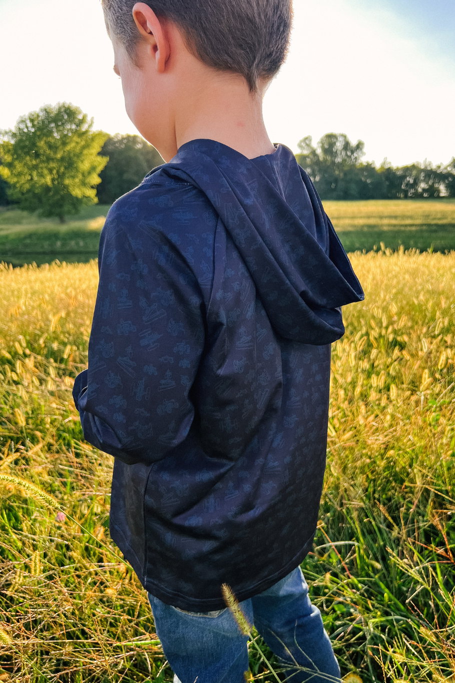 boy standing in a grass field in a blue performance hoodie