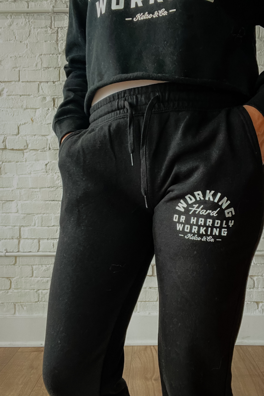 close up of black joggers on a model "working hard or hardly working" in white
