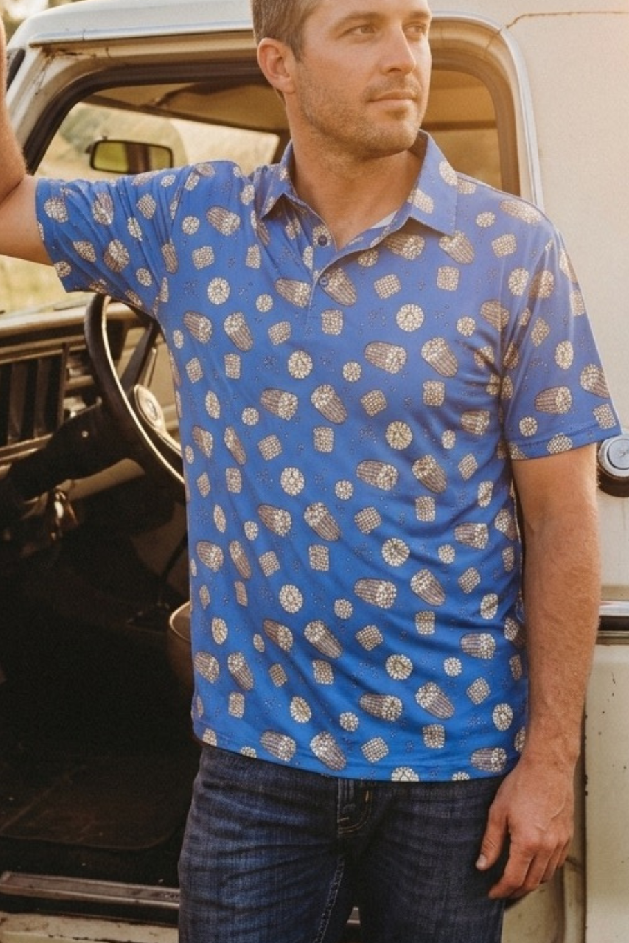 Man wearing a blue patterned corn cob shirt standing next to a vintage white truck