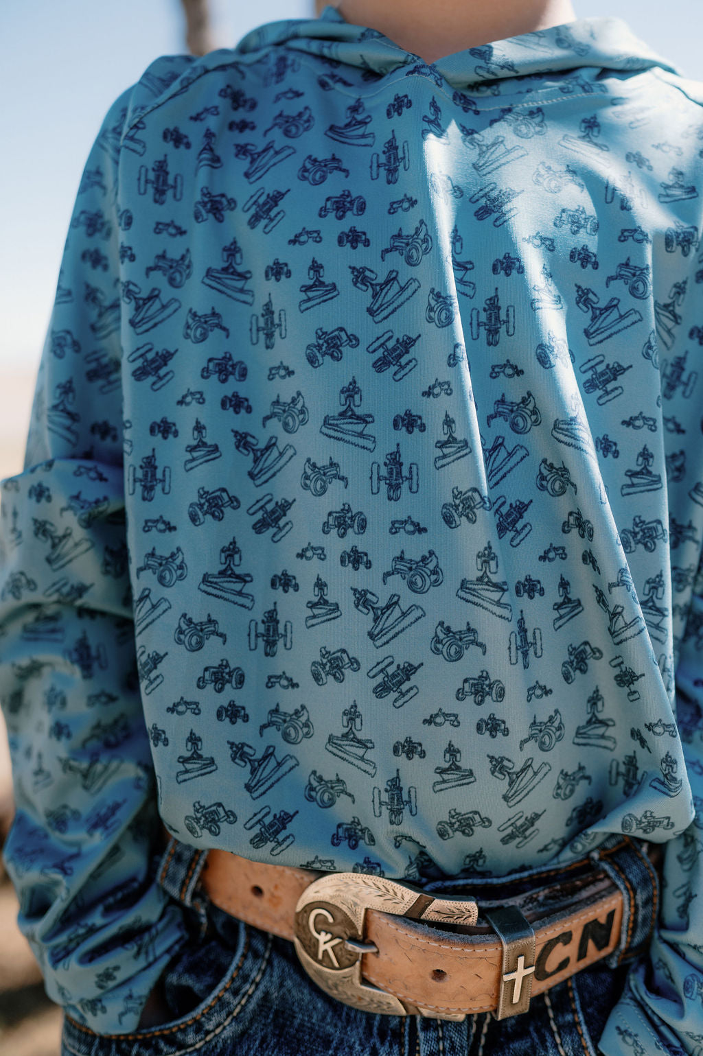 boy wearing a blue performance hoodie with dark blue tractors all over it 