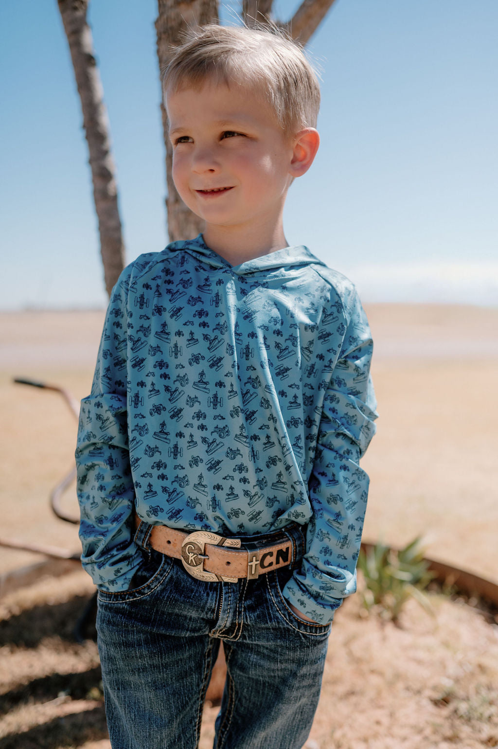 boy wearing a blue performance hoodie with dark blue tractors all over it 