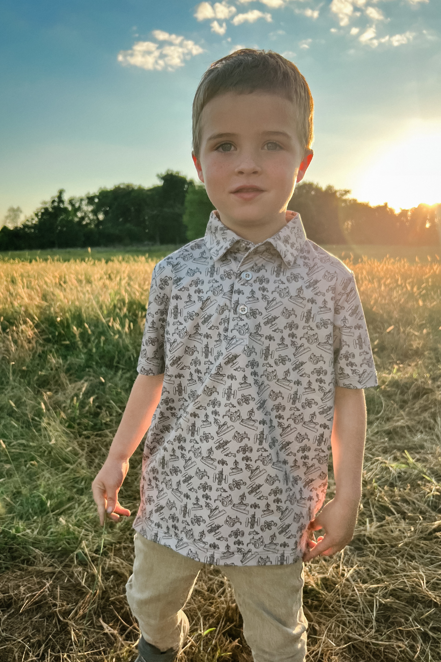 boy wearing a tractor performance polo in a grass field