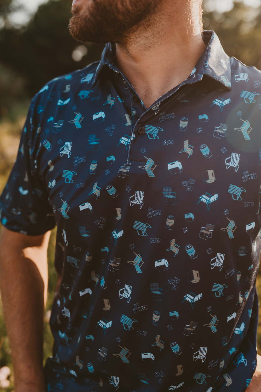pattern of vintage lawn chairs, coolers, ice and a lager on a men's performance polo in dark blue