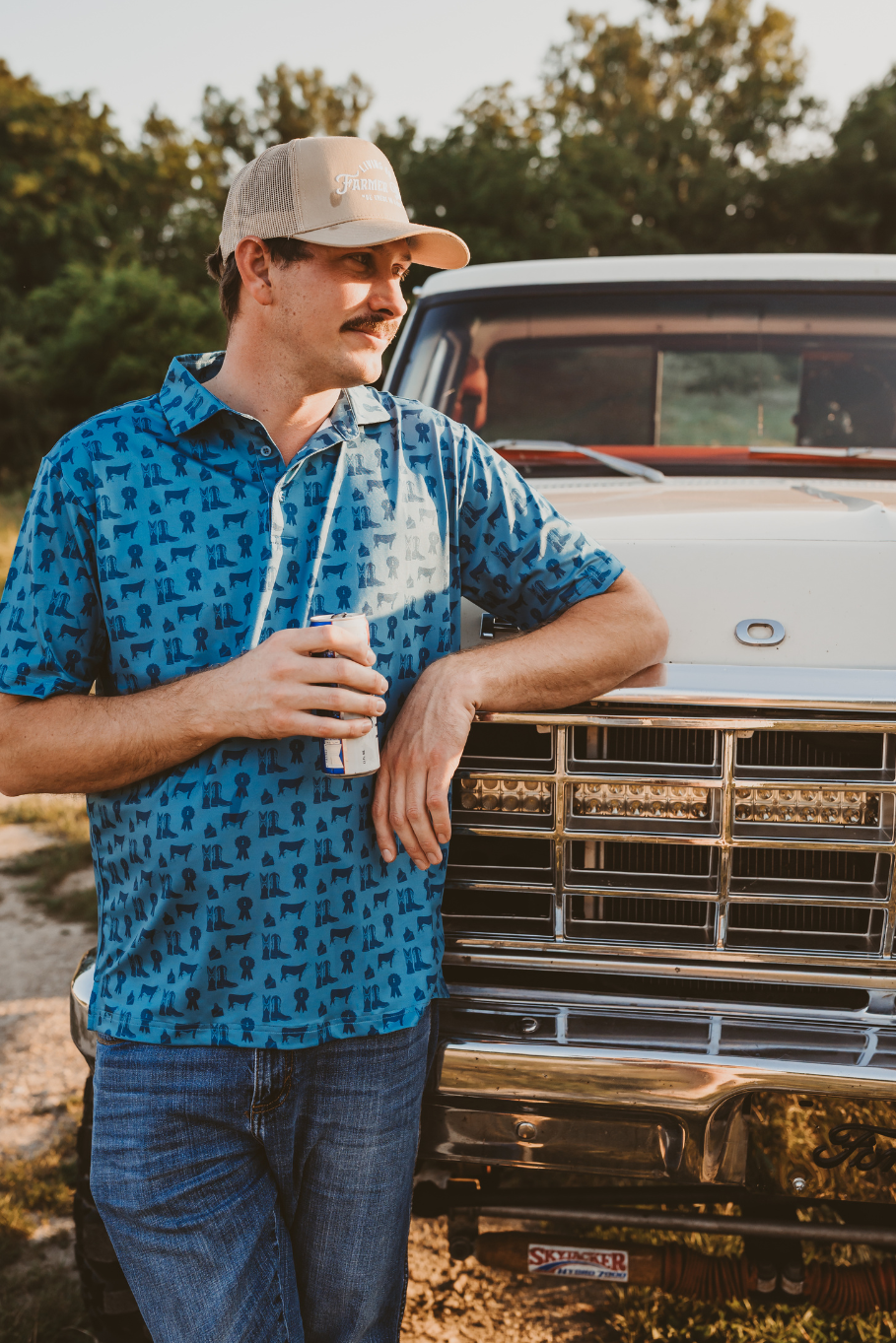 county fair mens performance polo in blue with hereford cattle, cowboy boots and blue ribbons