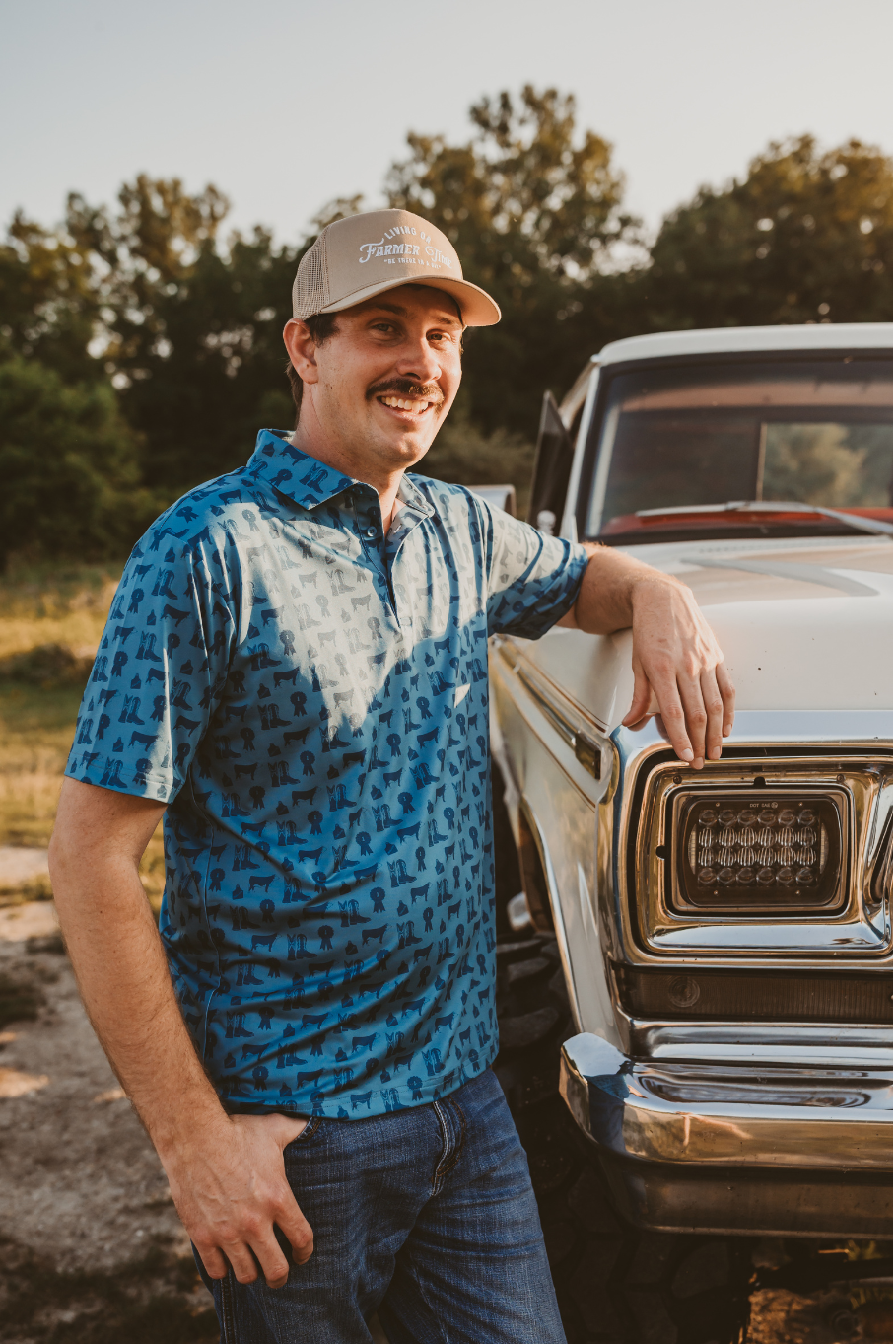 county fair mens performance polo in blue with hereford cattle, cowboy boots and blue ribbons