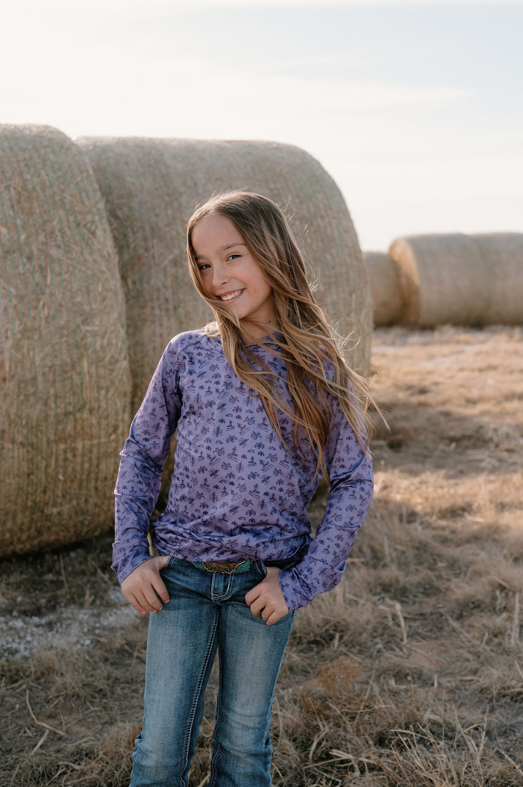 girl on a farm wearing a purple performance hoodie with dark purple antique tractor pattern