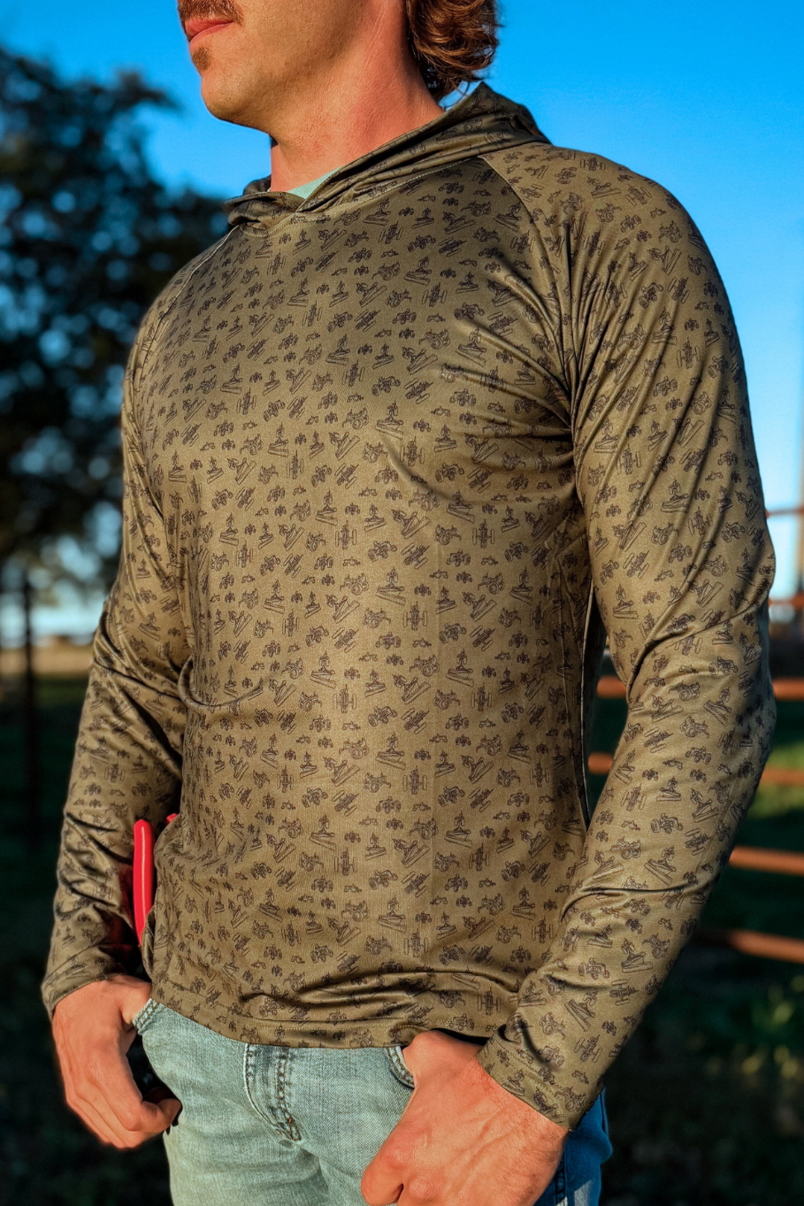 man on farm wearing green performance hoodie with blue antique tractor print