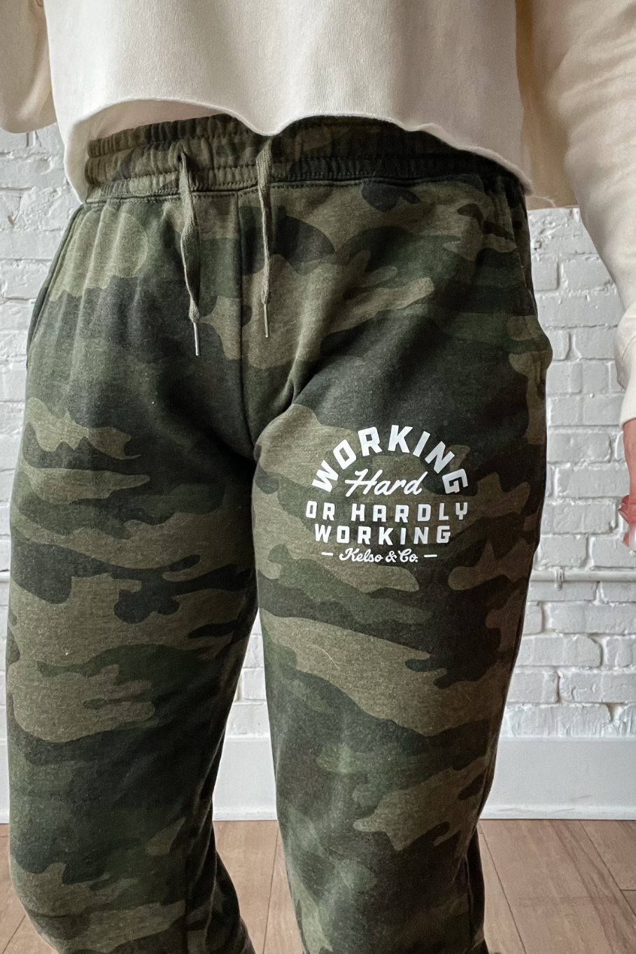 close up of kelso and co camo joggers with working hard or hardly working graphic in white on left thigh near pocket