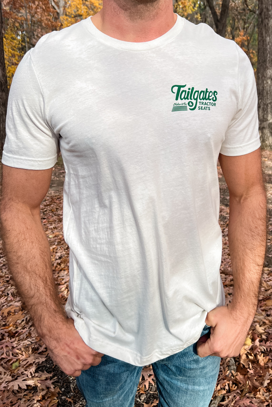 front of guy wearing vintage white tshirt that says tailgates and tractor seats in green on the left chest