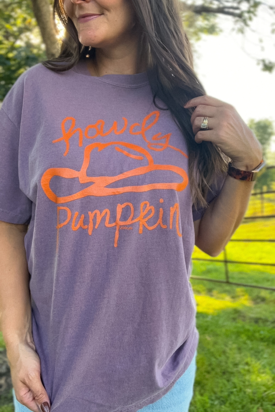 dusty purple comfort colors tshirt with rust cowboy hat graphic that says "howdy pumpkin"