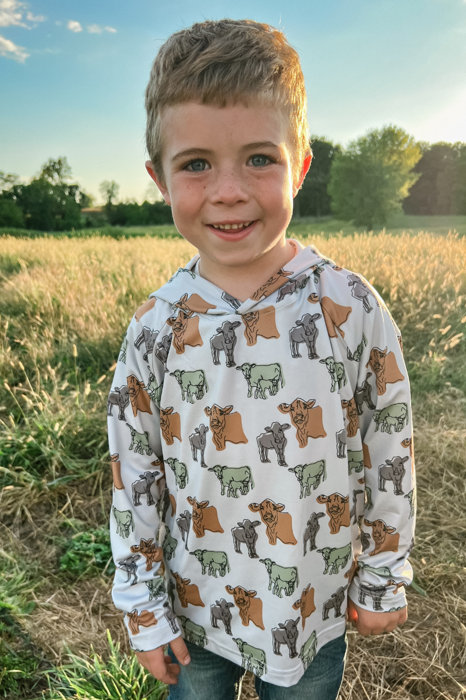 boy wearing cow performance hoodie in a hay field