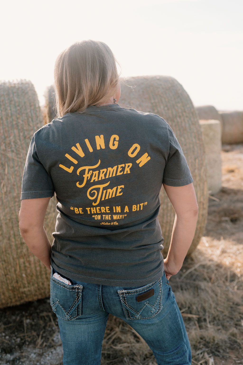 woman wearing pepper gray colored tshirt with yellow graphic "living on farmer time" on the back