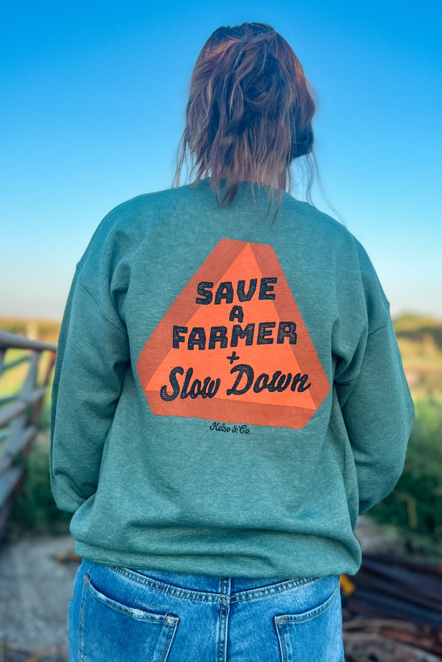 back of heather green crewneck with slow moving vehicle sign that says save a farmer and slow down