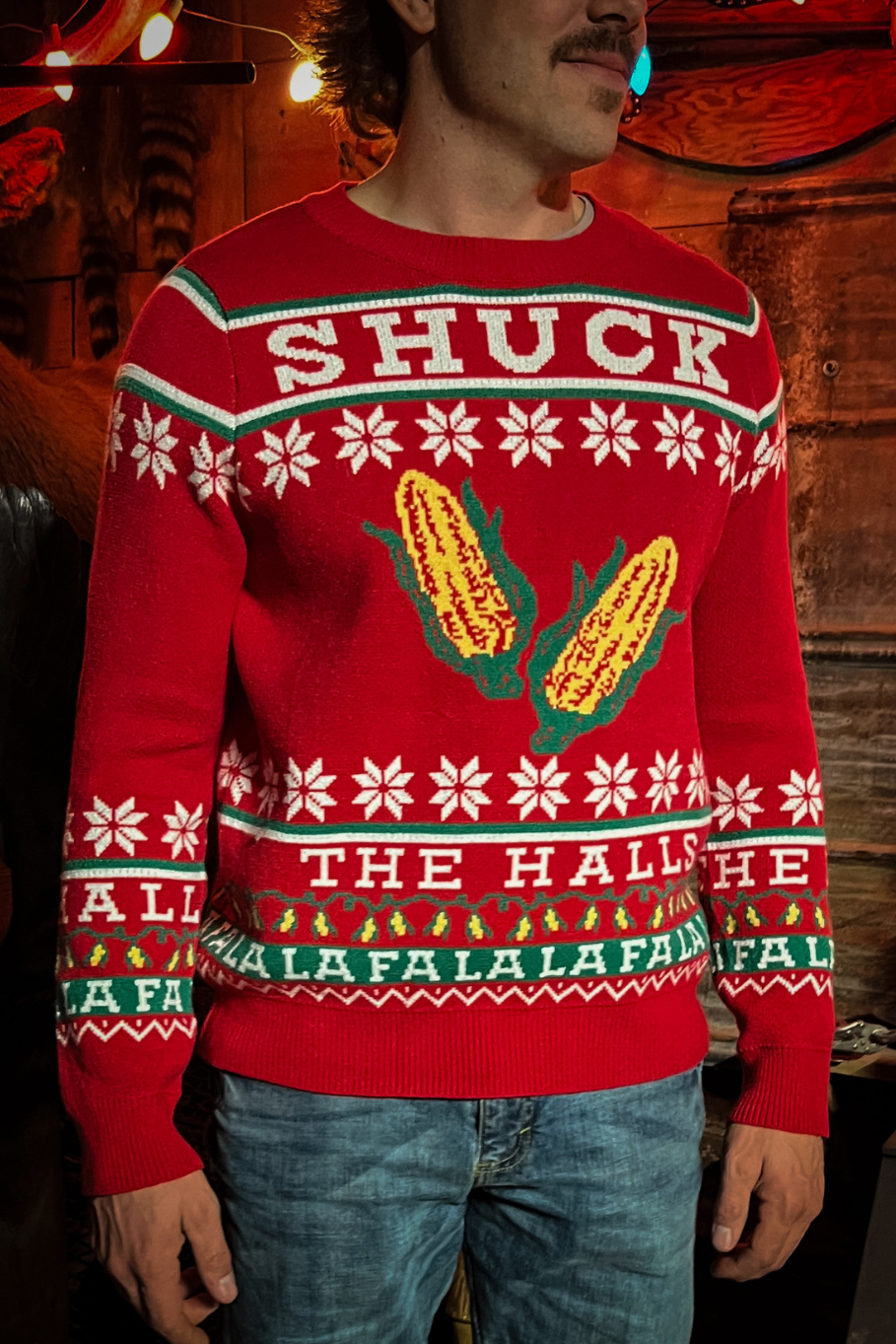 guy wearing a red holiday sweater with ears of corn that says &quot;shuck the halls&quot;