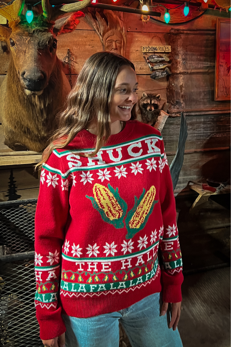 woman wearing red holiday sweater with ears of corn that says &quot;shuck the halls&quot;