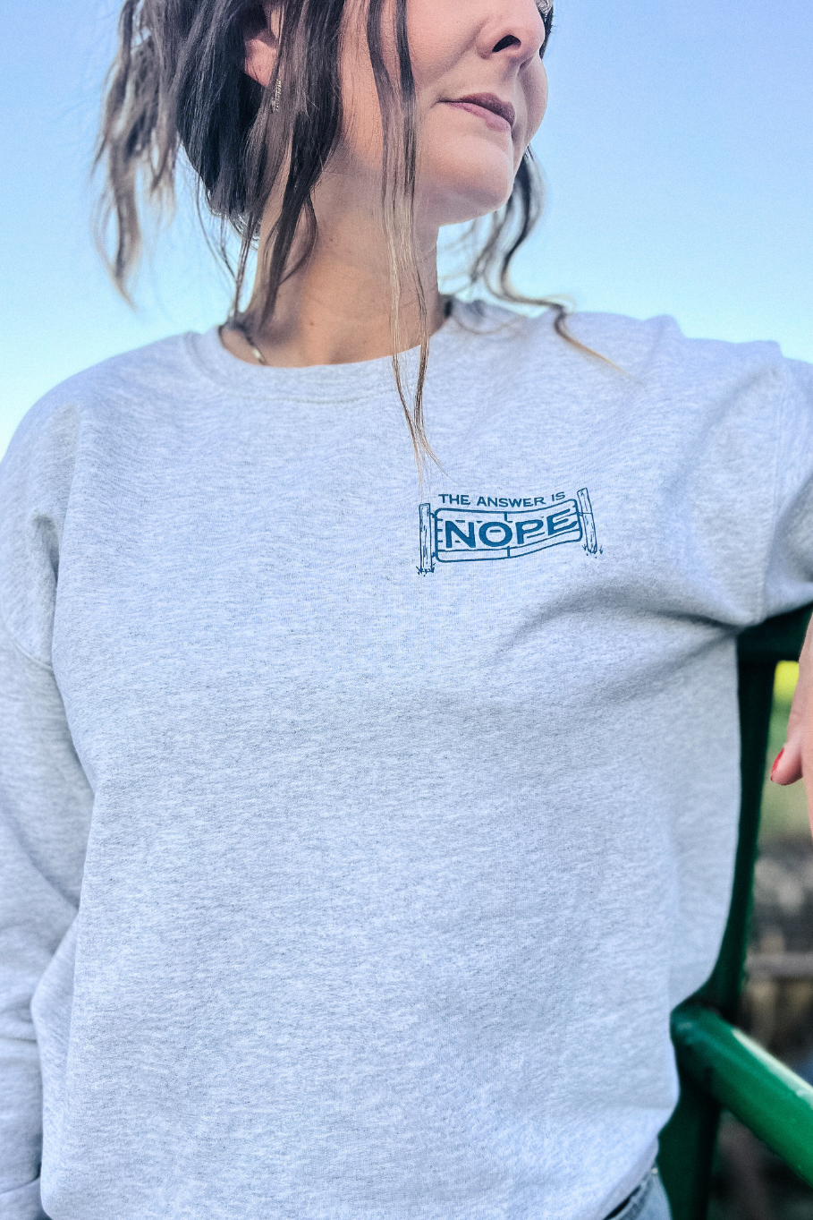 front of ash gray crewneck with left crest gray print the answer is nope with a livestock gate