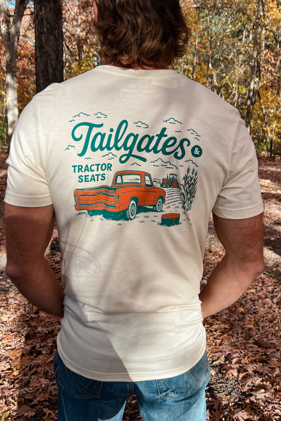 back of guy wearing soft cream tshirt with orange and teal graphic of old pick up truck and a tractor in the field - tailgates and tractor seats