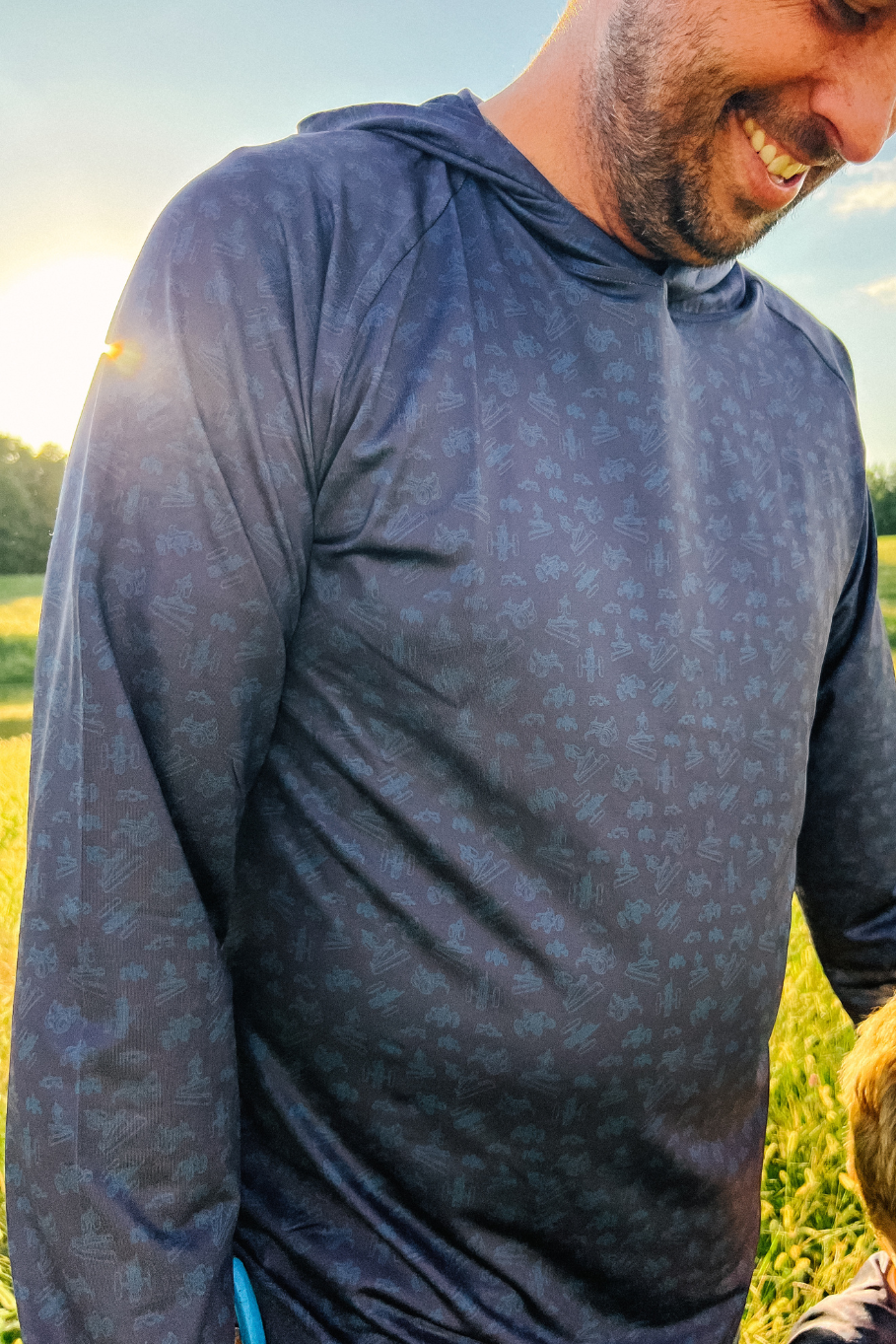 Man wearing a blue long-sleeve shirt with a pattern, standing outdoors with a blurred background