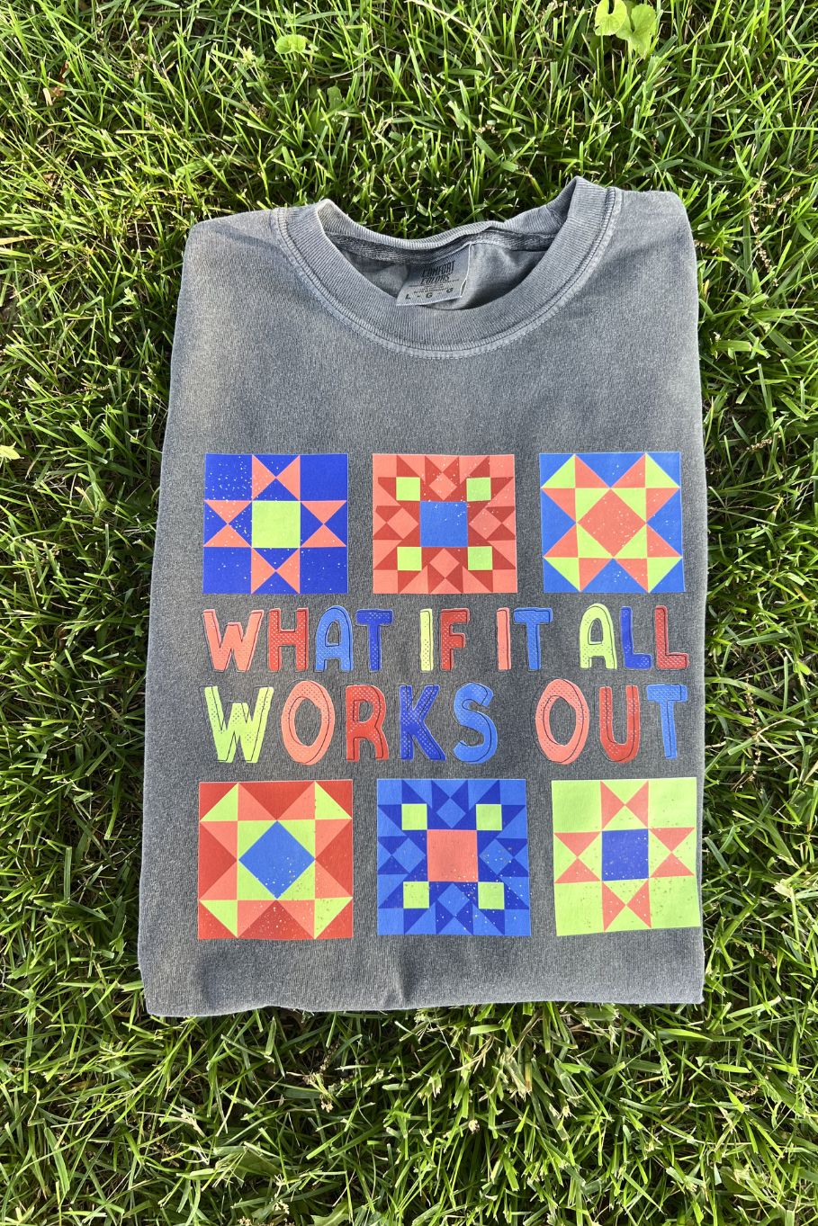 folded comfort colors graphic tee with multi colored barn quilt design that says "what if it all works out"