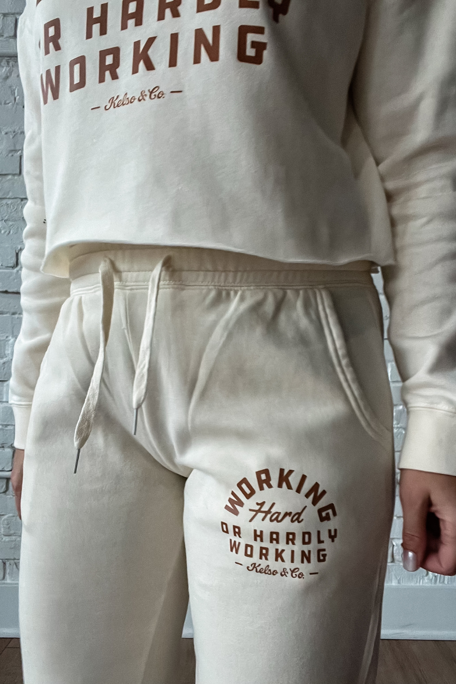 close up of top of bone joggers with graphic "working hard or hardly working"